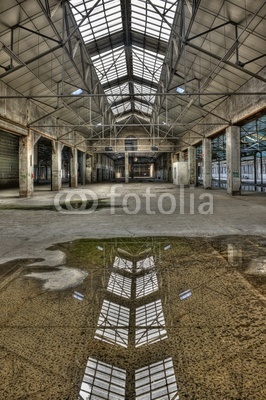 Abandoned old industrial building with reflection in a puddle