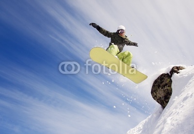 Snowboarder jumping through air with  blue sky in background