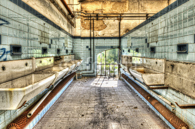 Derelict washbasins in the communal shower room of an abandoned